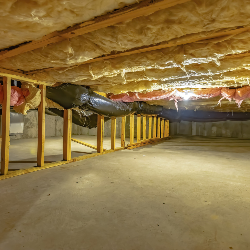 A clean, unfinished crawl space with exposed wooden framing, insulation in the ceiling, and ductwork running along the top. Concrete floor and concrete walls are visible.